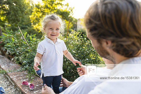 Porträt eines glücklichen kleinen Mädchens mit Eltern in einem Park