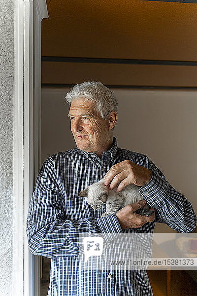 Älterer Mann zu Hause hält Kätzchen