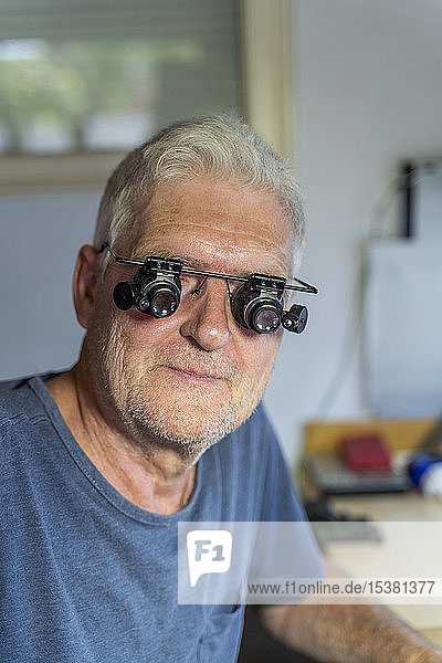 senior man wearing magnifying specracles  portrait