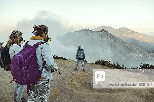 Family with respirator masks standing at the edge of volcano Ijen Java Indonesia