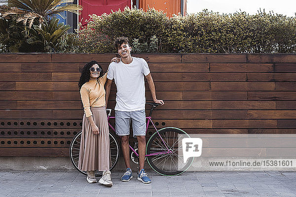 Glückliches Paar mit Fahrrad  an der Wand stehend