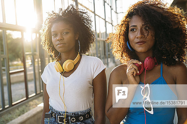 Porträt von zwei jungen Frauen mit Kopfhörern bei Sonnenuntergang