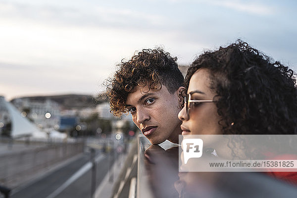 Junges Paar auf der Brücke  Kinn auf dem Geländer ruhend