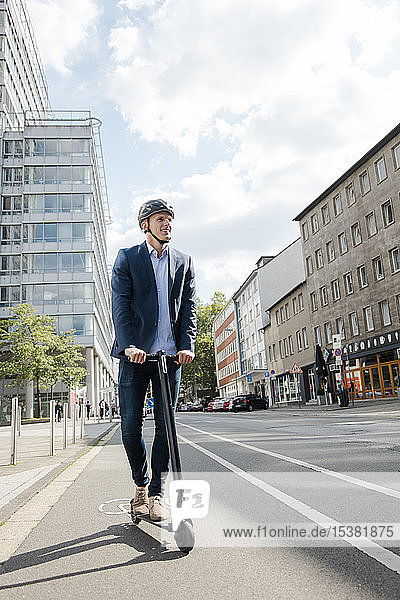 Junger Geschäftsmann auf dem E-Scooter auf dem Fahrradweg in der Stadt