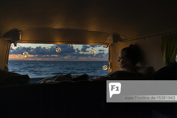 Woman in a van looking sideways at sunset