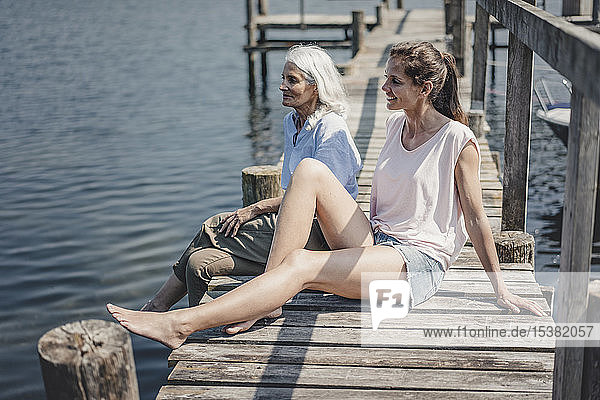Mutter und Tochter sitzen auf einem Steg und entspannen sich am Meer