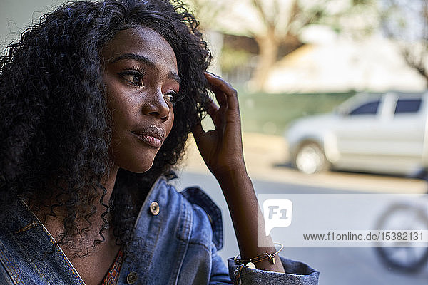 Porträt einer jungen Afrikanerin in einem Cafe  die aus dem Fenster schaut