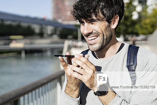 Glücklicher Mann benutzt Smartphone in der Stadt