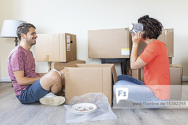 Glückliches Paar zieht in ein neues Zuhause ein und packt einen Karton aus