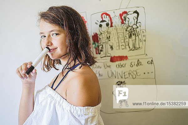Portrait of smiling girl drawing on a whiteboard