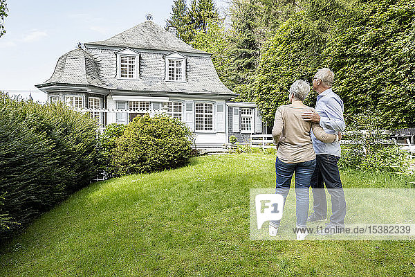Rear view of senior couple standing in garden of their home