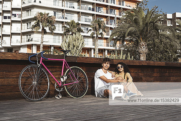 Junges Paar mit Fahrrad sitzt in der Stadt und unterhält sich