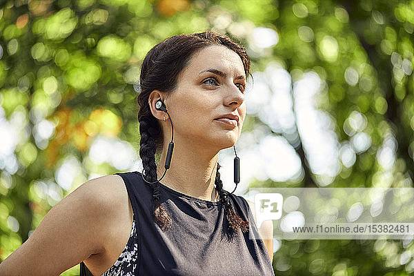 Porträt einer sportlichen jungen Frau mit Kopfhörern im Wald