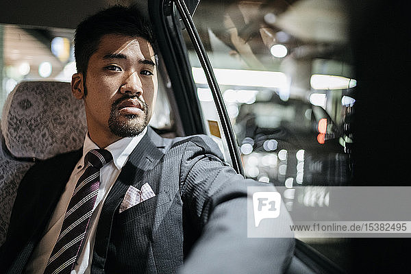Porträt eines selbstbewussten jungen Geschäftsmannes in einem Taxi