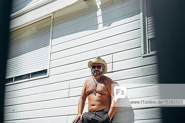 Mann mit Cowboyhut steht neben seinem Haus