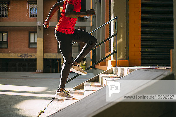 Junger sportlicher Mann rennt auf einer Außentreppe die Treppe hinauf