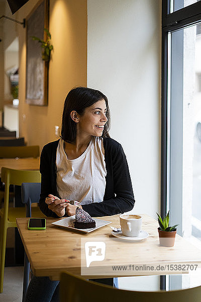 Smiling young woman in a cafe looking out of window