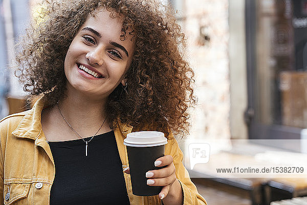 Portrait of happy teenage girl with coffee to go