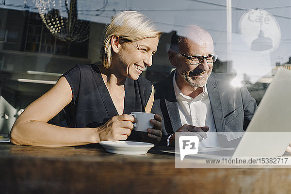 Businessman and woman sitting in coffee shop  using laptop
