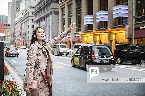 Junge Frau  die an einer Straße in Ginza  Tokio  Japan  ein Taxi ruft