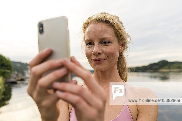 Junge Frau telefoniert mit ihrem Handy an einem See