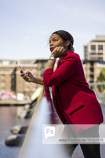 Porträt einer nachdenklichen Geschäftsfrau  die am Brückengeländer lehnt und nach oben schaut  London  UK