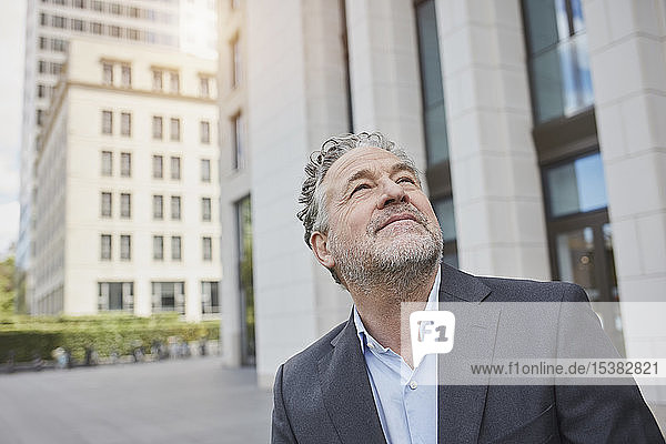 Porträt eines selbstbewussten Geschäftsmannes in der Stadt mit Blick nach oben