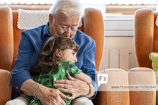 Großmutter umarmt ihre Enkelin im Wohnzimmer