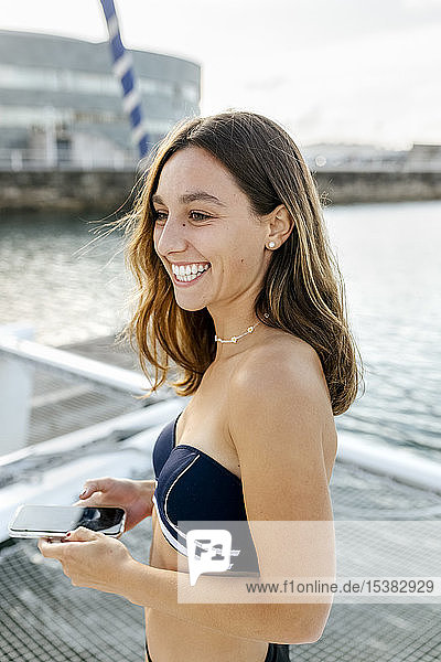 Junge schöne Frau mit Smartphone auf einem Segelboot