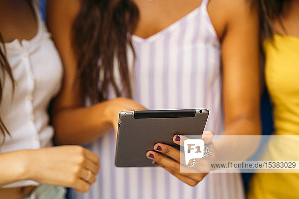 Close-up of three young women sharing a tablet