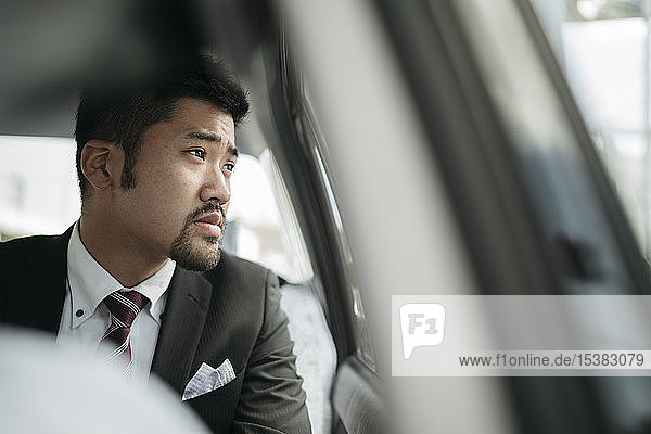 Young businessman in a taxi looking out of window