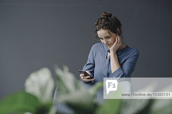 Porträt einer jungen Frau  die auf ein Handy schaut