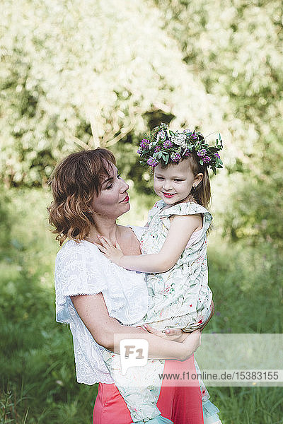 Mother holding daughter with flower wreath