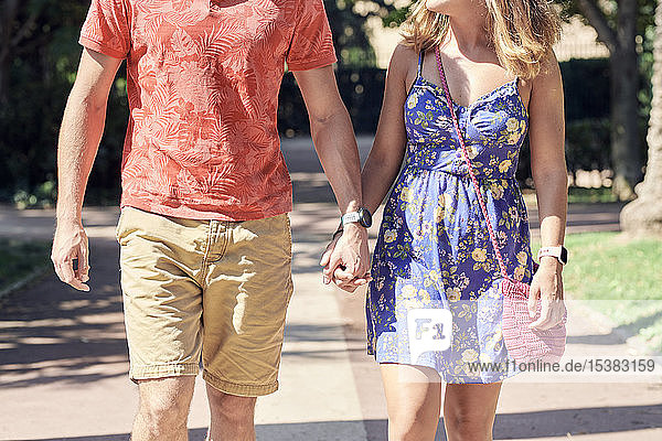 Junges Paar geht Hand in Hand durch einen Park