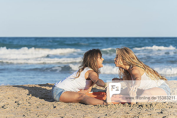 Zwei Frauen praktizieren Acro Yoga am Strand