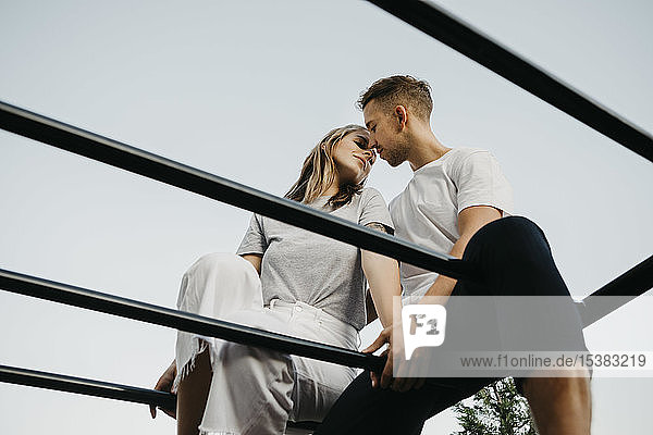Junges Paar küsst sich auf einem Klettergerüst