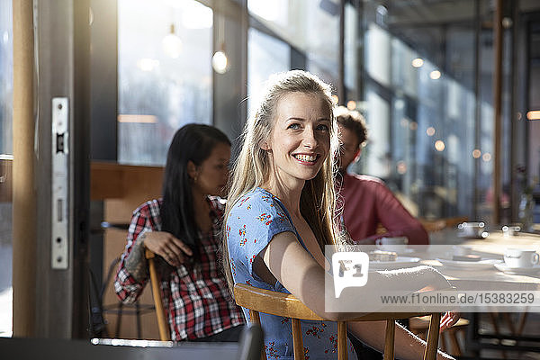 Porträt einer lächelnden Frau mit Freunden in einem Cafe