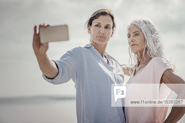 Mutter und Tochter verbringen einen Tag am Meer  nehmen sich ein Smartphone