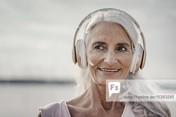 Ältere Frau beim Musikhören mit Kopfhörern am Meer  poartrait