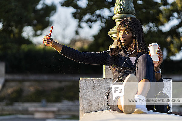 Smiling businesswoman sitting outdoors making a selfie
