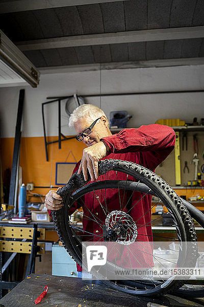 Älterer Mann repariert Fahrradreifen in Werkstatt