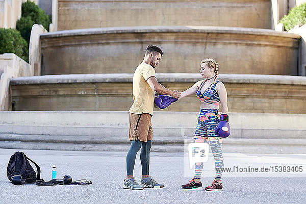 Fitnesstrainer übt Boxunterricht mit einer jungen Frau im Freien in der Stadt die einen Boxhandschuh anzieht