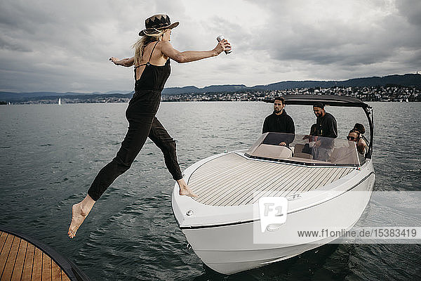 Junge Frau springt auf ein Boot auf einem See