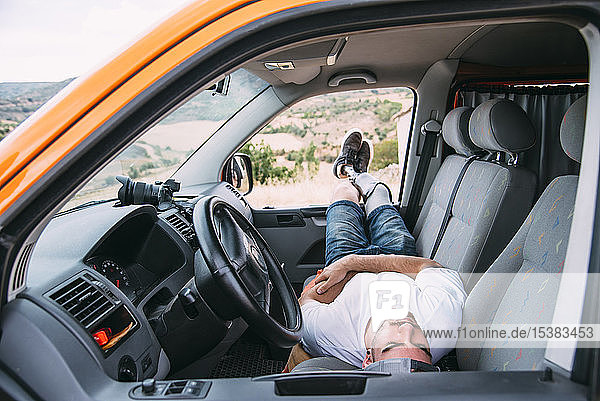 Young man with leg prosthesis resting in camper van