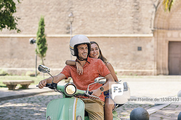Junges Paar auf einem Oldtimer-Motorroller im Freien