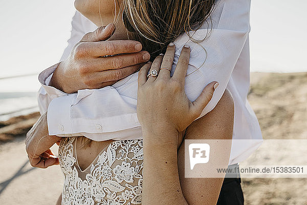 Close-up of affectionate bride and groom hugging outdoors