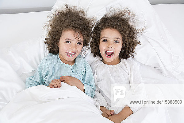 Porträt von zwei glücklichen Zwillingsbrüdern im Bett liegend