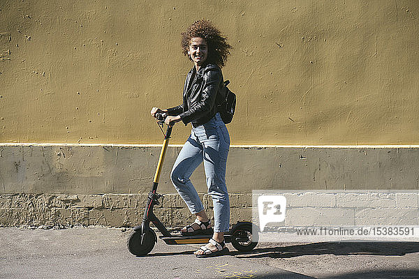 Smiling teenage girl with scooter in the city