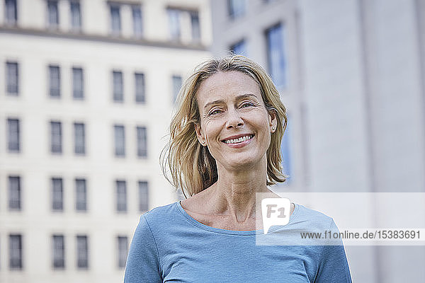 Porträt einer lächelnden blonden Frau in der Stadt