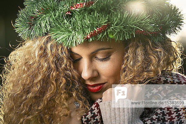 Portrait of smiling young woman wearing Christmas wreath on her head